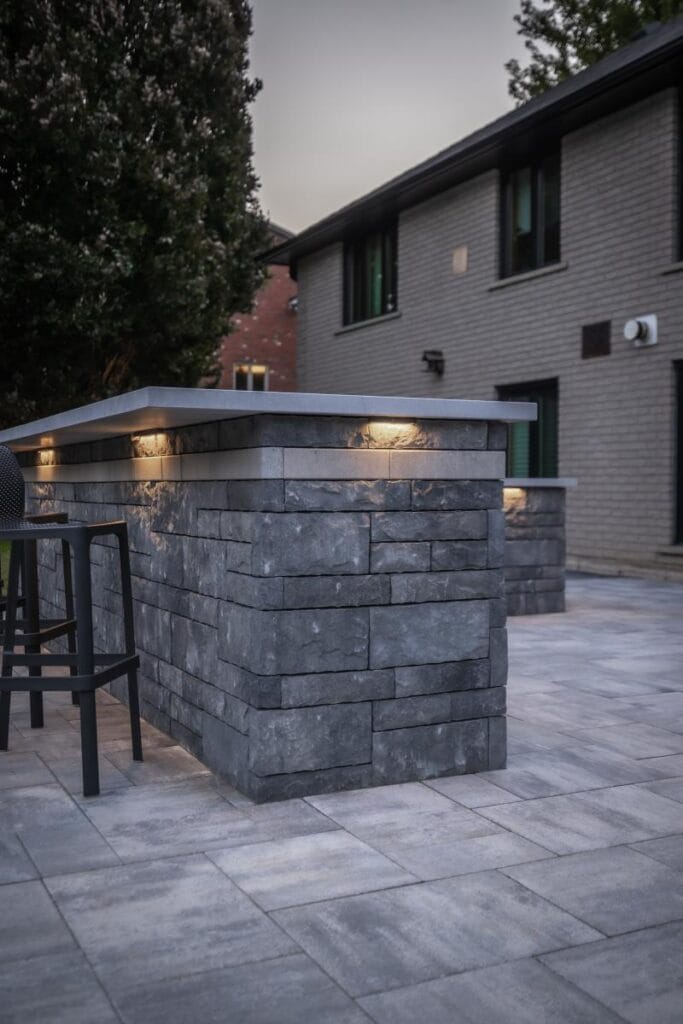 Outdoor kitchen bar area with stone counters and patio seating